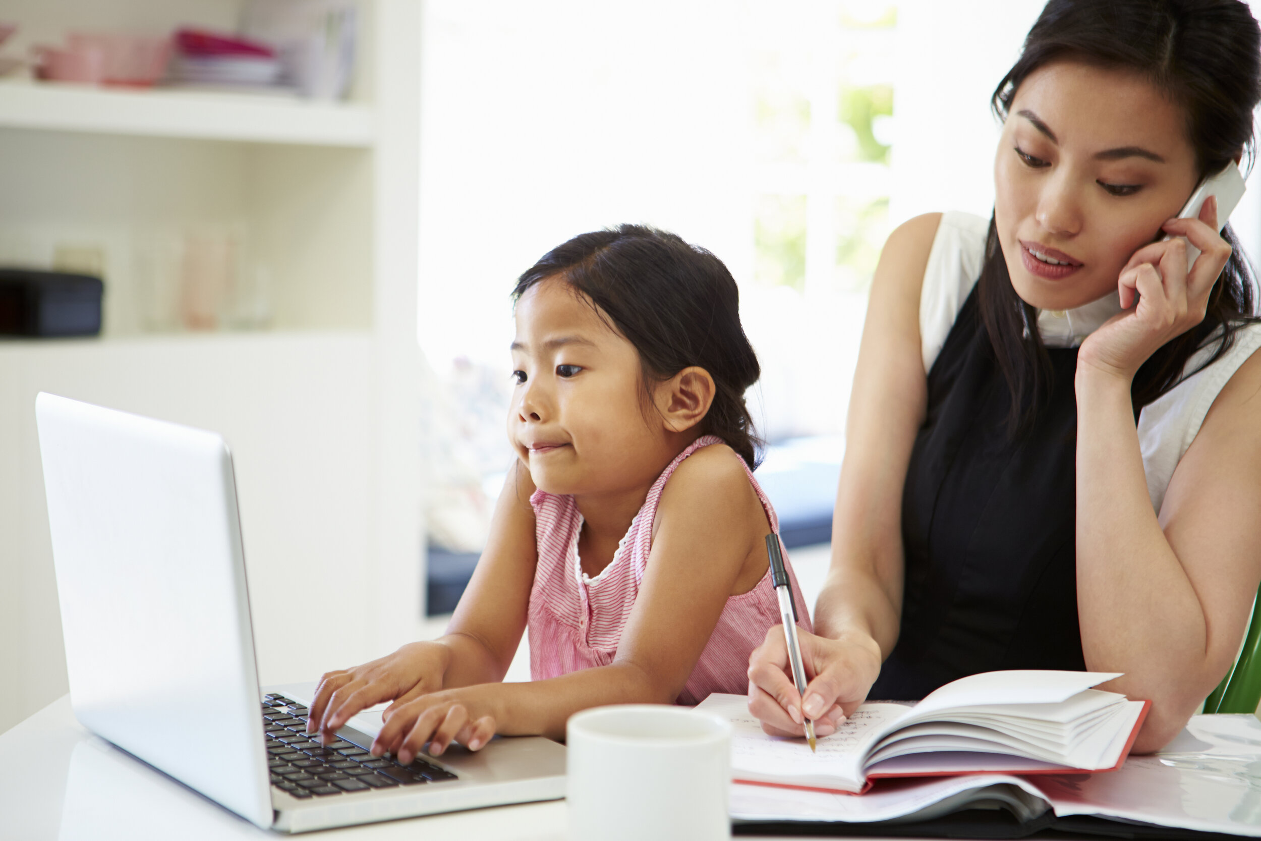 Kids or career - mom working on phone while child plays with laptop
