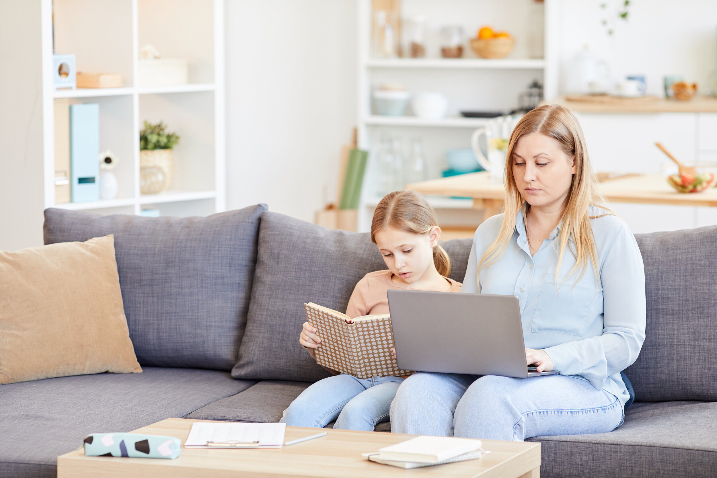 Kids or Career - mom working on computer on couch next to child reading
